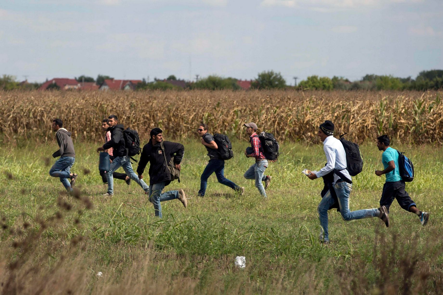 Migrants run across field